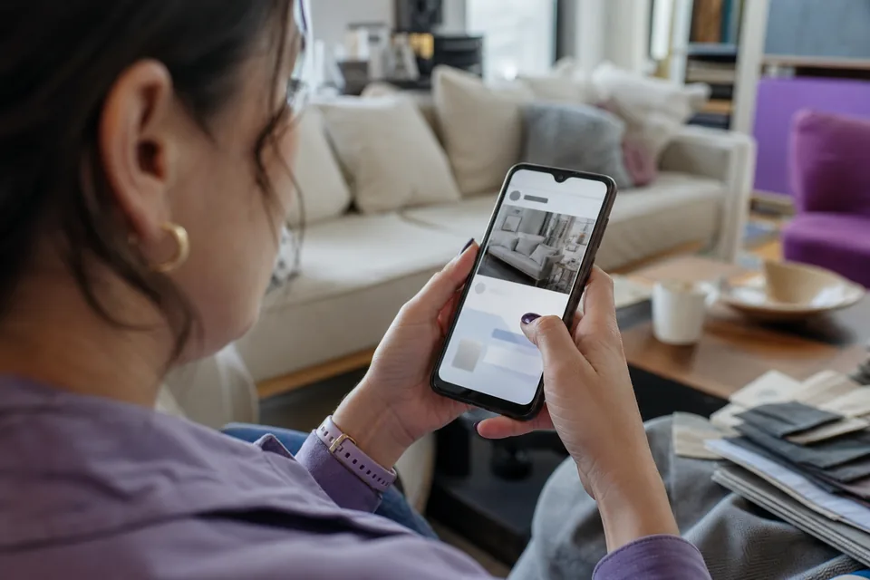 Telefon z reklamą sofy w mediach społecznościowych w dłoni klientki